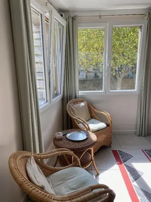 a room with two chairs and a table and two windows at L'esplanade, appartement en centre-ville au calme in Puisserguier