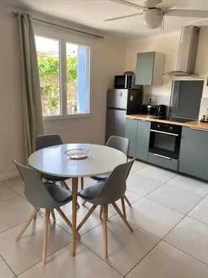 a kitchen with a table and chairs in a room at L'esplanade, appartement en centre-ville au calme in Puisserguier
