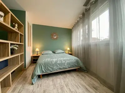 a bedroom with a bed with a green wall at L'Appartement Jebari - Esprit loft Carcassonne proche cité médiéval et aéroport in Carcassonne