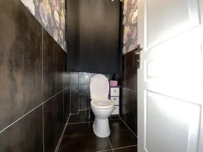 a bathroom with a toilet and a black wall at L'Appartement Jebari - Esprit loft Carcassonne proche cité médiéval et aéroport in Carcassonne