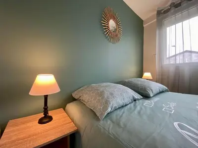 a bedroom with a bed and a table with a lamp at L'Appartement Jebari - Esprit loft Carcassonne proche cité médiéval et aéroport in Carcassonne