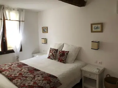a white bedroom with a bed and a window at Charmante maison de village avec toit terrasse in Montalba-le-Château