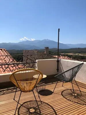 two chairs and a table on a wooden deck at Charmante maison de village avec toit terrasse in Montalba-le-Château