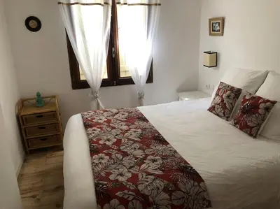 a bedroom with a bed with a red blanket and a window at Charmante maison de village avec toit terrasse in Montalba-le-Château