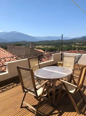 a table and chairs on a deck with a view at Charmante maison de village avec toit terrasse in Montalba-le-Château