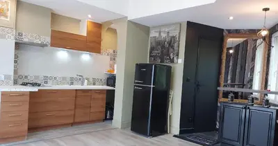 a kitchen with a black refrigerator and wooden cabinets at T2 tout confort, parking gratuit, vue lac et nature in Revel
