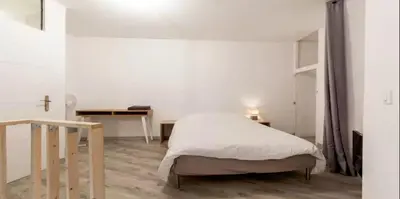a white bedroom with a bed and a table at DUPLEX DU GET in Revel