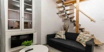 a living room with a black couch and a staircase at DUPLEX DU GET in Revel