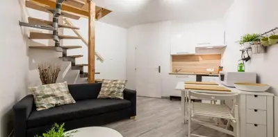 a living room with a black couch and a kitchen at DUPLEX DU GET in Revel