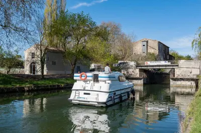 a white boat is docked on a river at LE MOULIN DU VIVIER in Saint-Martin-Lalande