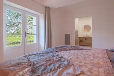 a bedroom with a large bed and a window at LE MOULIN DU VIVIER in Saint-Martin-Lalande