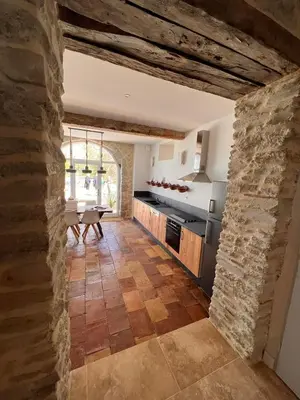 a large kitchen with a stone wall and a table at LE MOULIN DU VIVIER in Saint-Martin-Lalande