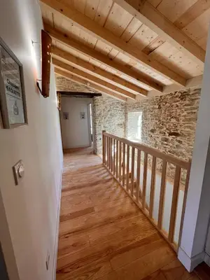 a hallway with a staircase in a stone building with wooden ceilings at LE MOULIN DU VIVIER in Saint-Martin-Lalande