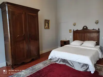 a bedroom with a bed and a large wooden cabinet at GITE Le Logis Barbès in Carcassonne