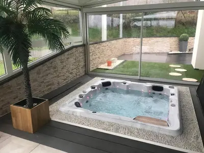 a hot tub in a room with a palm tree at Koh Samui Siam Manahakhon Appart & Spa in Rieux-de-Pelleport