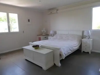 a white bedroom with a bed and two windows at La Maison Barthélemy: Voie Verte et piscine in Bellegarde-du-Razès