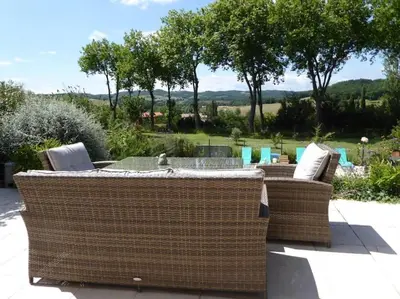 a patio with two wicker chairs and a table at La Maison Barthélemy: Voie Verte et piscine in Bellegarde-du-Razès