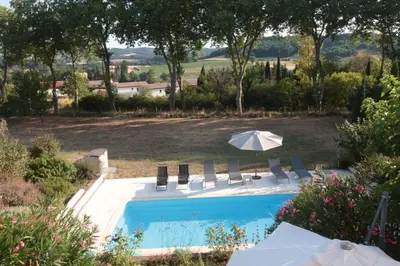 a swimming pool with chairs and an umbrella at La Maison Barthélemy: Voie Verte et piscine in Bellegarde-du-Razès