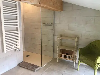 a shower with a glass door and a chair at La Souqueto in Mirepeisset