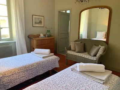 a bedroom with two beds and a mirror and a chair at La Souqueto in Mirepeisset