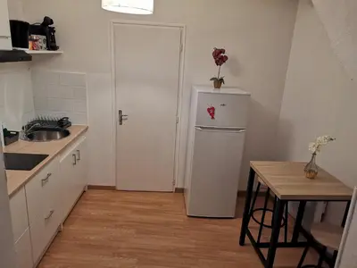 a small kitchen with a refrigerator and a table at Studio au cœur du quartier historique in Narbonne
