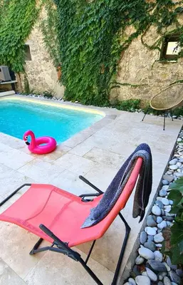 a pink chair sitting next to a swimming pool at Appartements cocons dans les Corbières in Villesèque-des-Corbières