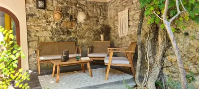 a patio with two chairs and tables and a stone wall at Appartements cocons dans les Corbières in Villesèque-des-Corbières
