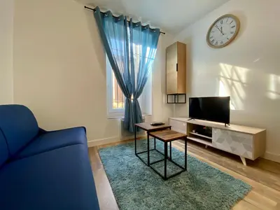 a living room with a tv and a blue couch at Zen appart - 35m2 à Carcassonne in Carcassonne