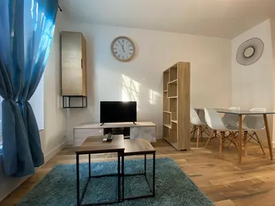 a living room with a table and a clock on the wall at Zen appart - 35m2 à Carcassonne in Carcassonne