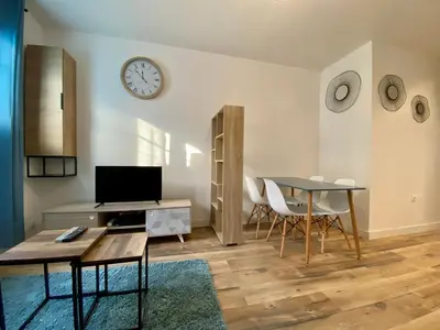 a living room with a table and a clock on the wall at Zen appart - 35m2 à Carcassonne in Carcassonne