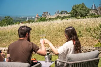 a man and woman sitting at a table with wine glasses at L'écrin de la Cité, Grand Panorama, vue unique sur les remparts de Carcassonne in Carcassonne
