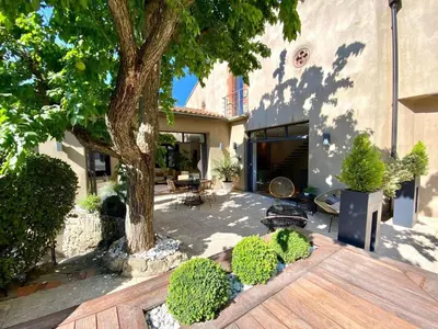 a backyard with a tree and a wooden deck at House Avenue in Carcassonne