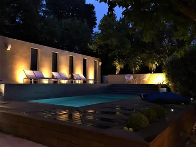a swimming pool with lounge chairs in a backyard at night at House Avenue in Carcassonne