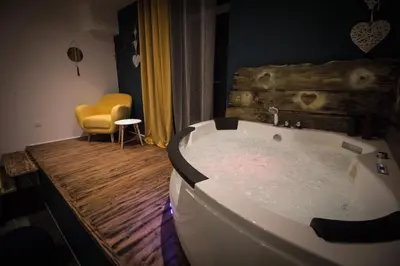 a bath tub in a room with a yellow chair at Au Canal du Midi - Appartements au cœur de la ville in Carcassonne