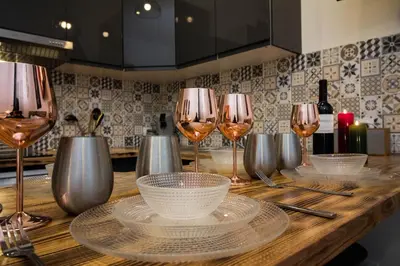 a wooden table with wine glasses and plates on it at Au Canal du Midi - Appartements au cœur de la ville in Carcassonne