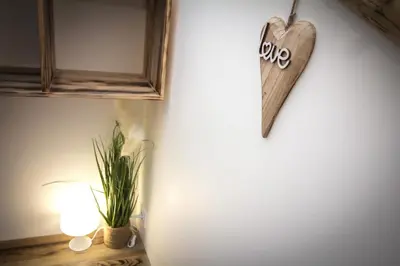 a wooden heart hanging on a wall with a plant at Au Canal du Midi - Appartements au cœur de la ville in Carcassonne