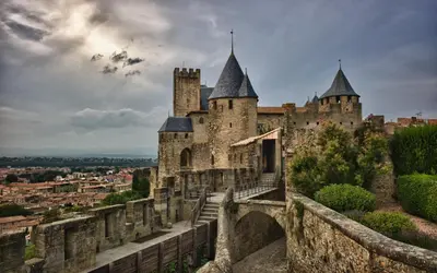 an old castle with a staircase in front of a city at Au Canal du Midi - Appartements au cœur de la ville in Carcassonne