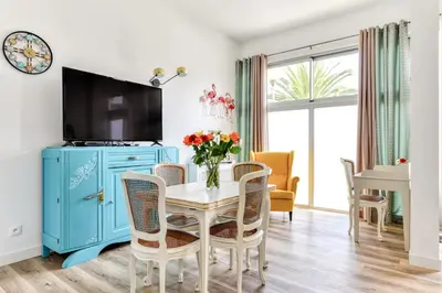 a dining room with a blue cabinet and a table with flowers at Loft Plage du Grazel in Gruissan