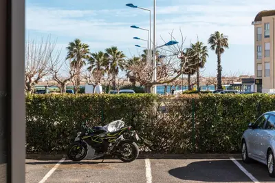a motorcycle parked in a parking lot next to a hedge at Loft Plage du Grazel in Gruissan