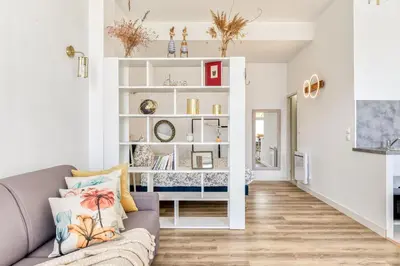 a living room with a couch and a book shelf at Loft Plage du Grazel in Gruissan