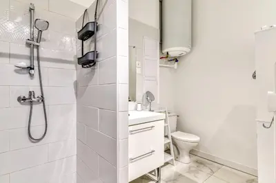a white bathroom with a shower and a toilet at Loft Plage du Grazel in Gruissan