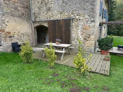 a wooden deck with a picnic table in front of a building at Gîte La Glycine in Dun