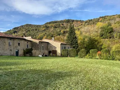 an old stone house with a grassy yard at Gîte La Glycine in Dun