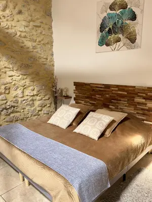 a bedroom with a bed with a stone wall at LE PETIT CLOS in Fontjoncouse