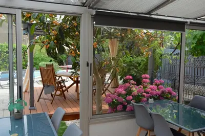 a screened porch with pink flowers and a table and chairs at LE PETIT CLOS in Fontjoncouse