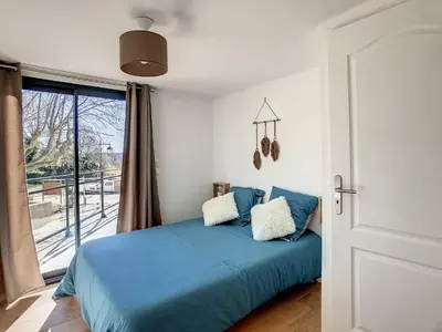 a bedroom with a blue bed and a balcony at ** Superbe appartement sur le canal du midi ** in La Redorte
