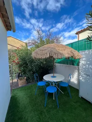 a table and chairs under a straw umbrella at Studio RIQUET indépendant attenant à Villa in Capestang