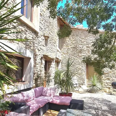 a couch sitting in front of a stone building at Villa Misanid écrin de verdure à 15mm de la cité de Carcassonne in Mas-des-Cours