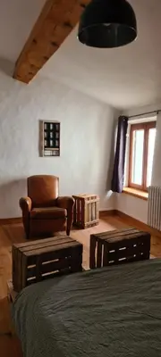a living room with a chair and a table at Villa Misanid écrin de verdure à 15mm de la cité de Carcassonne in Mas-des-Cours