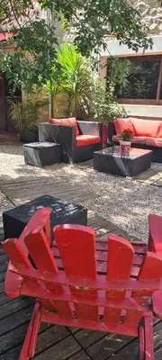 a red bench sitting in a courtyard with furniture at Villa Misanid écrin de verdure à 15mm de la cité de Carcassonne in Mas-des-Cours